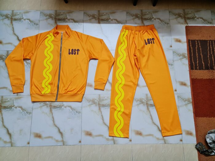 A bright orange tracksuit displayed on a flat surface, showcasing its modern design and comfortable fit, ideal for both exercise and leisure.